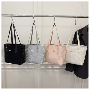 Detail of minimalist tote bags in four colors with embossed marble texture on metal rack