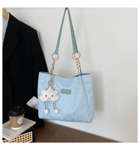 Dettaglio borsa tote azzurra con motivo a stelle, catena e ciondolo a nuvola di peluche