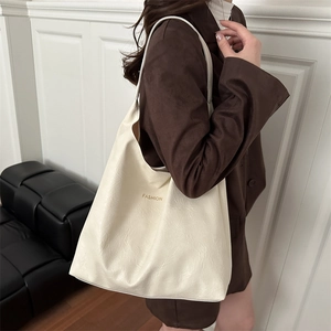 Minimalist beige PU leather tote bag with gold FASHION logo shown on shoulder