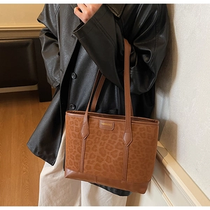 Brown leopard print tote bag with leather bottom shown as a stylish shoulder bag