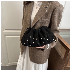 Detail of black suede drawstring bucket bag with decorative gold metal rivets