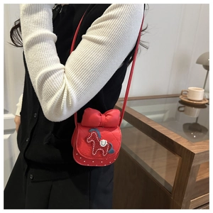 Detail of red quilted mini crossbody bag featuring a 3D bow and pony embroidery