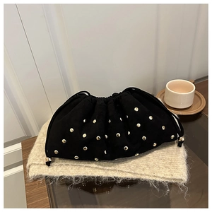 Close-up of black suede bucket bag with gold rivets on soft knitted scarf