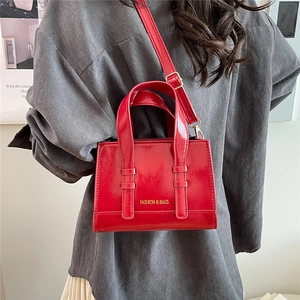 Polished red oil wax leather handbag for women featuring gold-tone hardware and top handles