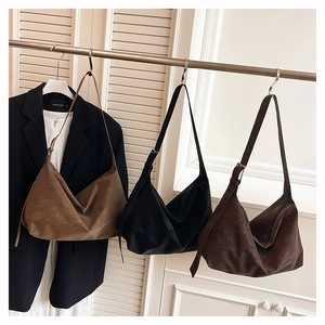 Trois grands sacs hobo en daim marron et noir suspendus à un support de vêtements