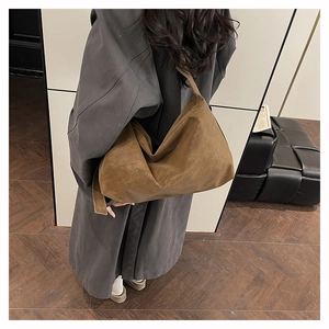 Sac cabas vintage en daim marron porté par un mannequin avec un élégant manteau gris
