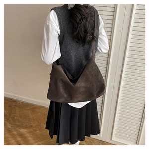 Vue détaillée du dos d'un grand sac cabas en cuir mat marron foncé porté par un modèle