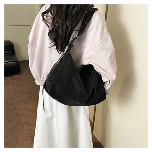 Vue arrière du mannequin portant un grand sac hobo noir mat avec large bandoulière