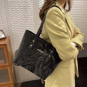 Minimalist black tote bag with marble texture and gold accents worn by a model