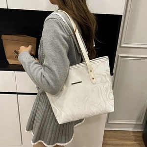Minimalist white marble pattern tote bag with gold hardware shown on a female model
