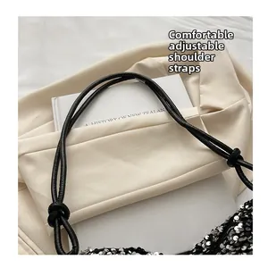 Detail of adjustable shoulder strap and silver sequins on black tote handbag