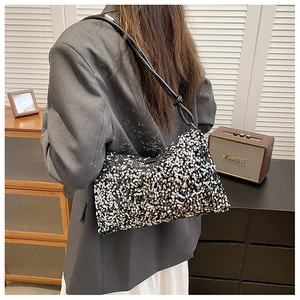 Close-up of a sequined shoulder bag featuring black and silver glitter texture with knotted strap