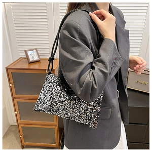 Detail of sequined shoulder bag with black strap worn over a grey blazer for a chic look
