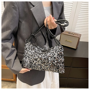 Close-up of sparkling sequin handbag with elegant black leather shoulder strap detail