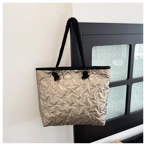 Star quilted champagne gold tote bag with black braided rope handles on window