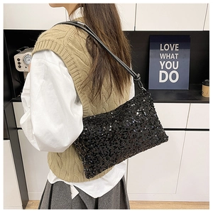 Detail of black sequin hobo bag with leather knotted strap worn on a woman's shoulder