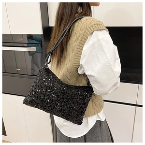 Close-up of black sequined underarm bag with sleek leather strap worn on shoulder