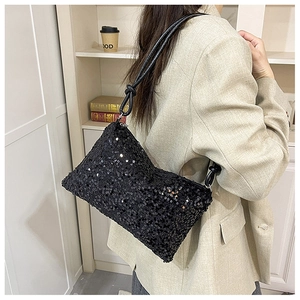 Detail of black sequined underarm bag with knotted shoulder strap and silver metal ring