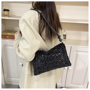 Detailed view of black sequined underarm bag with knot strap detail on shoulder