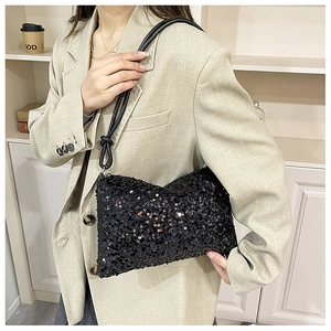 Close-up of black sequin handbag with leather knot strap on a beige blazer background