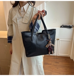 Détail du sac cabas en cuir noir avec pendentif lapin en tricot rouge sur bandoulières