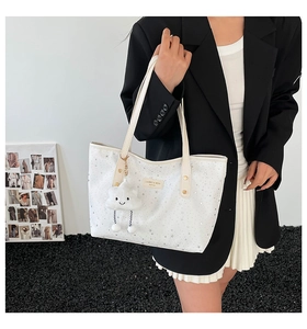 White tote bag with silver star prints and plush cloud charm held by a model