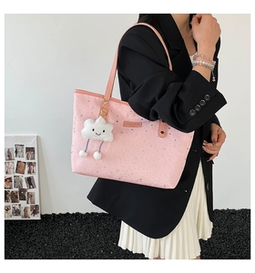 Detail of pink star-patterned tote bag with plush cloud charm and brown leather patch