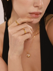 Close-up of golden wave rings stacked on a model to show minimalist titanium texture