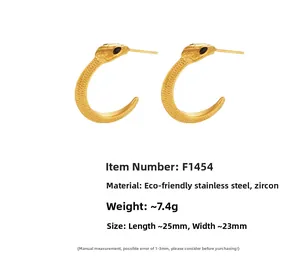 Détail macro de boucles d'oreilles serpent en acier doré avec zircons et fines écailles