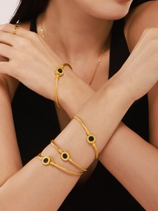 Detail of twisted gold bangle and ring set with black round shell inlay on model