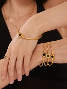 Close-up of gold twist texture bracelets with black shell inlay on a female model