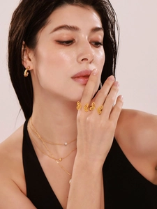Detail of 18K gold-plated butterfly ring and layered necklaces on a female model