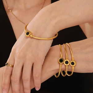 Golden twisted cable bracelet set with black enamel details on a female model