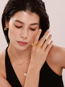 Detail of layered gold necklaces and butterfly rings set on a fashion model