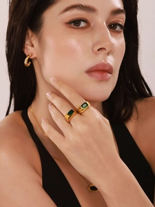 Nahaufnahme von vergoldetem Schmuckset mit grünen Zirkonia-Ringen und Creolen