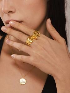Detalle de anillo con hebilla OT bañado en oro de 18k y collar de nácar en una modelo