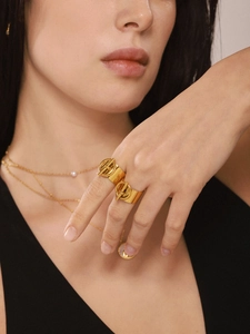 Detalle de anillo con cierre OT en acero bañado en oro de 18k y un collar con perlas