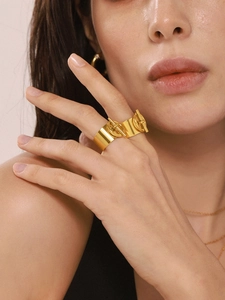 Detalle de anillo ancho en acero inoxidable bañado en oro de 18K con diseño de cierre OT