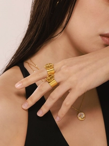 Detalle de un anillo ancho bañado en oro de 18K con diseño de hebilla OT en modelo