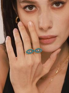 Macro detail of gold evil eye open ring with blue and white enamel glaze on a model's finger