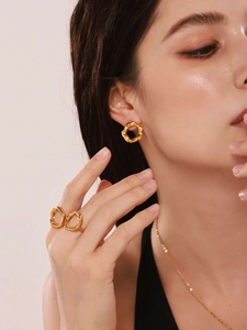Gros plan sur un ensemble de bijoux dorés géométriques irréguliers portés par un modèle