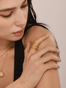 Close-up of polished gold geometric crossover ring and matching pendant on a model