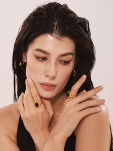 Close-up of gold stainless steel multi-band ring with oval black onyx and matching earrings