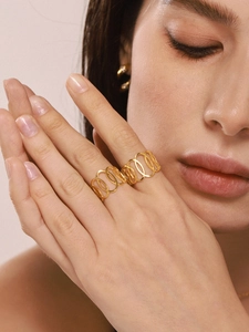 Gros plan d'une bague dorée ajourée sur un mannequin avec boucles d'oreilles
