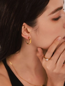 Detailed view of model wearing C-shaped diamond hoop earrings and a pearl gold ring