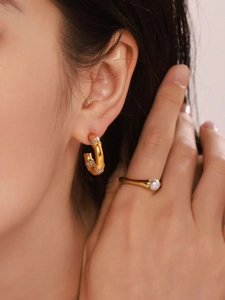Detailed close-up of golden bamboo-style C-hoop earrings with pave-set diamonds on model