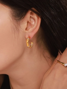 Detail of vintage bamboo style C-shaped gold earrings with sparkling pavé crystals