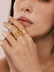 Gros plan d'une large bague géométrique en acier inoxydable doré PVD avec anneaux creux