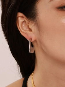 Close-up of a minimalist silver irregular geometric C-shaped earring on a model ear
