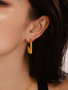 Close-up of irregular C-shape gold earrings with a modern liquid lava aesthetic design